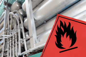 A flammable warning sign rests against some silver pipes